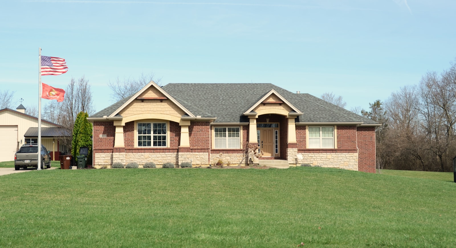 Brick ranch home with an American flag and a large green lawn, typical of St. Clair County, Illinois