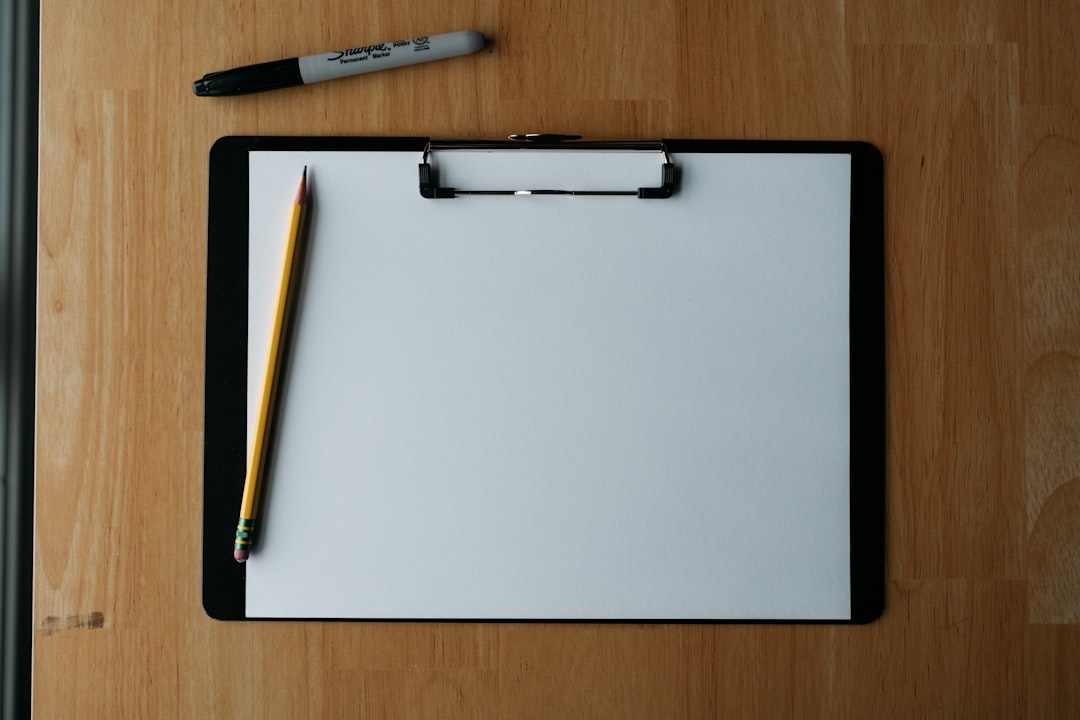 A blank clipboard with a pencil and marker on a wooden desk, for a home seller checklist