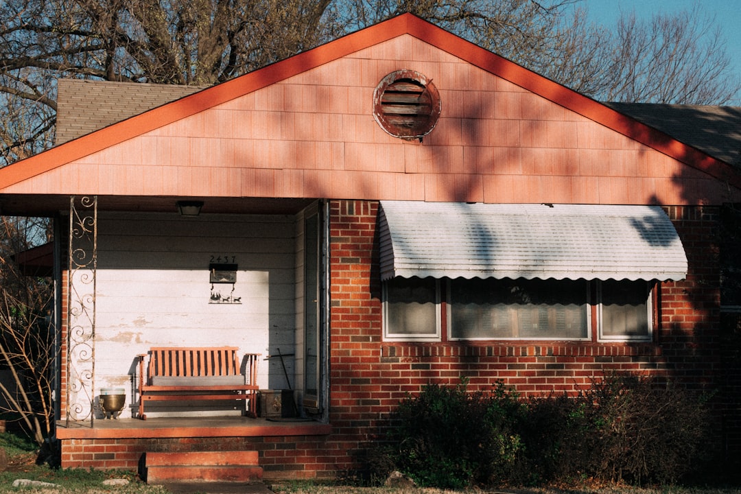 A brick ranch house with a front porch and awnings