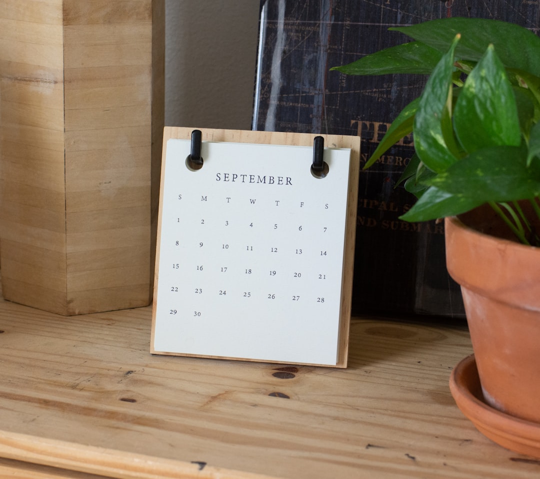 A small September desk calendar next to a potted plant, a reminder of a listing expiration date