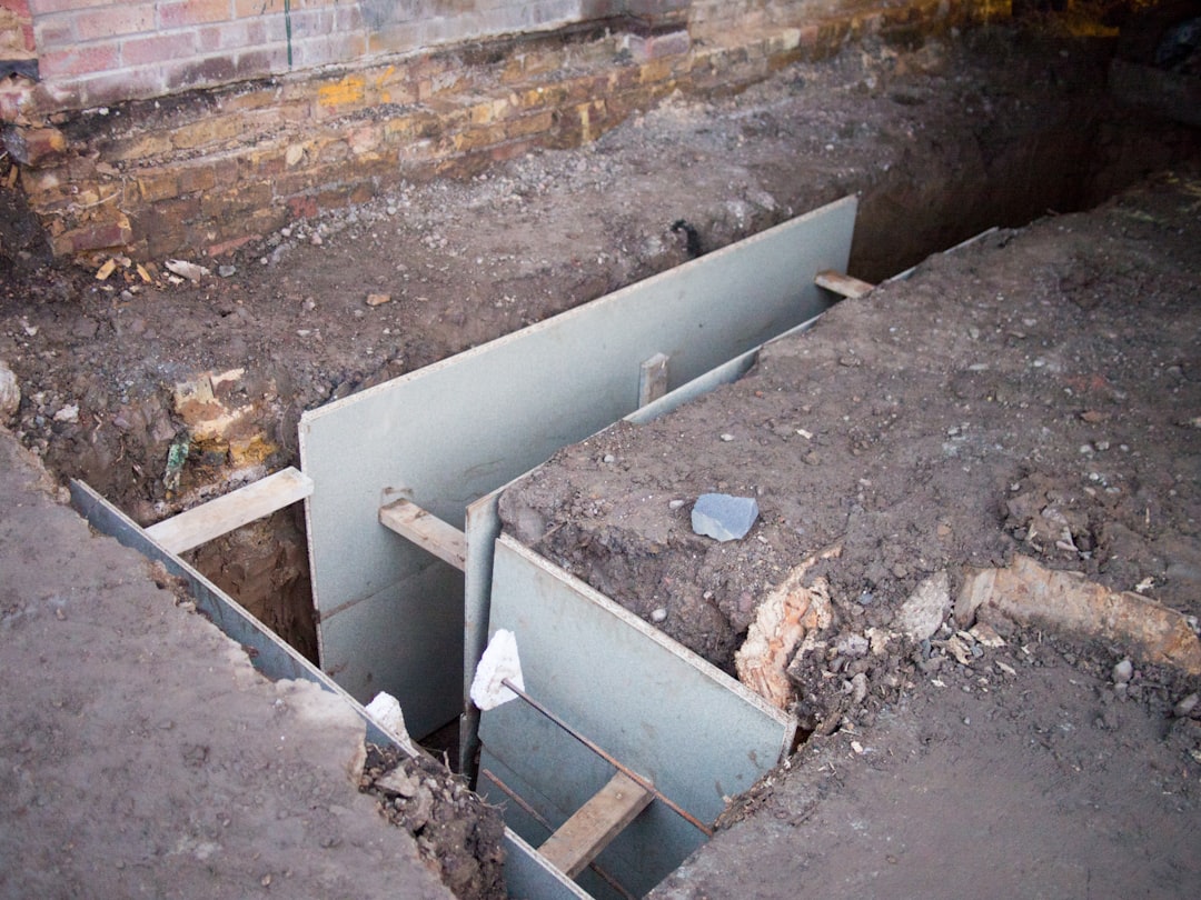 An excavated foundation trench next to a brick wall during foundation repair work