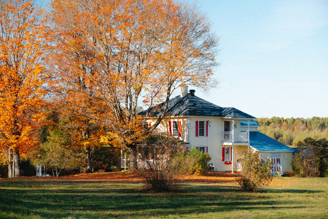 A two story house surrounded by autumn trees, a reminder that a fall closing still carries most of a year of property taxes