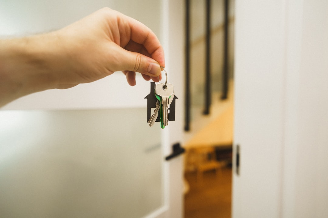 A hand holding a set of house keys in an open doorway on closing day
