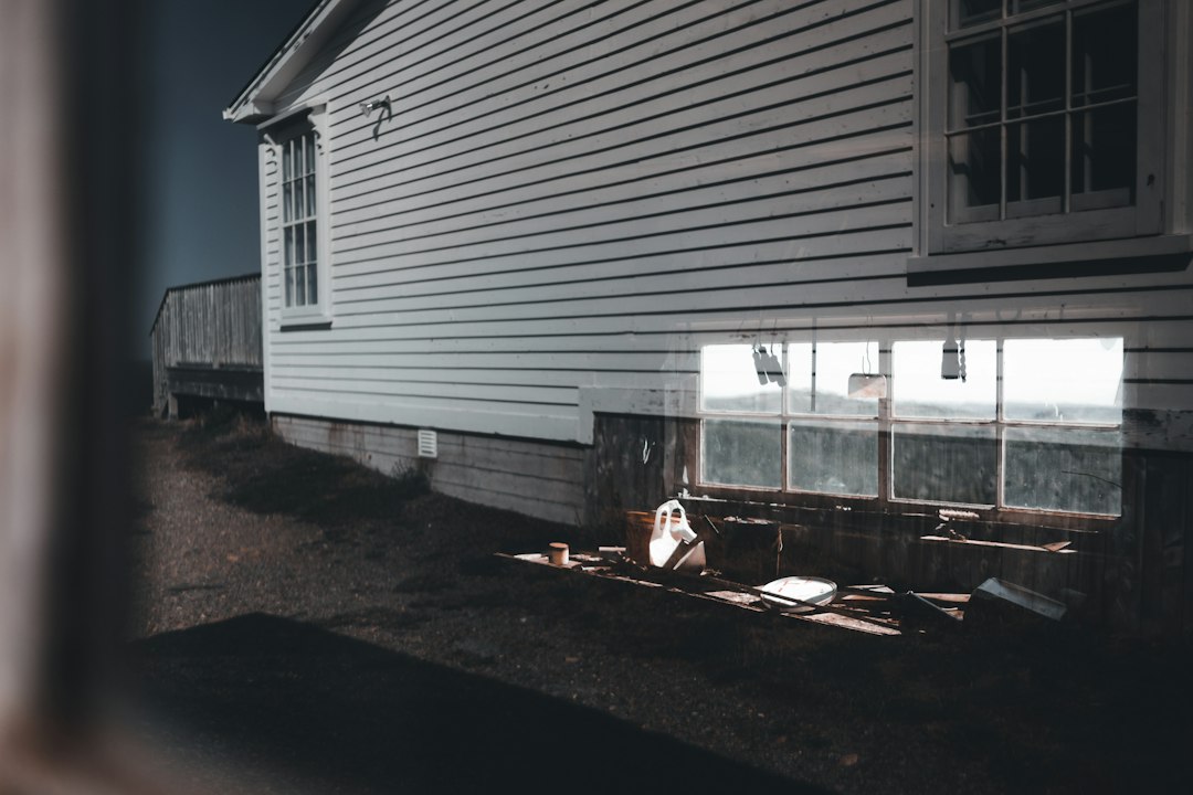 The side of a sided house with a lower level window, where radon and basement moisture questions start