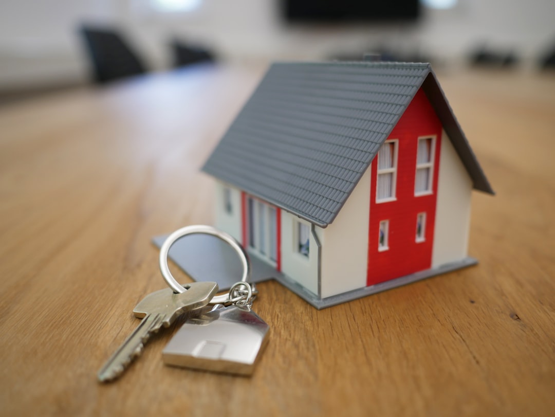 A small model house and a house key on a wooden table, representing seller closing costs